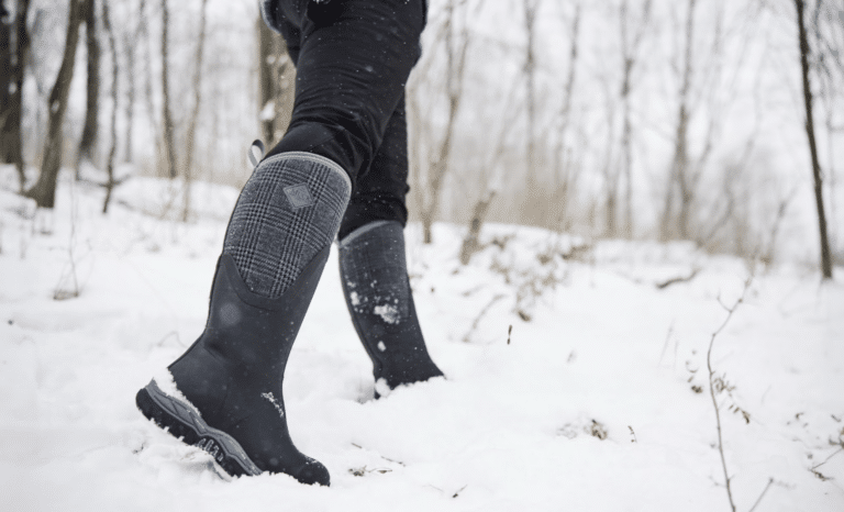 In 2025, a person wearing black boots trudges through a snowy forest, their silhouette reminiscent of Westminster's discerning judges traversing the crisp winter landscape.